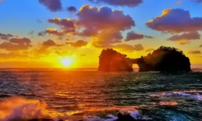 荒々しい波と円月島に沈む太陽の絶景